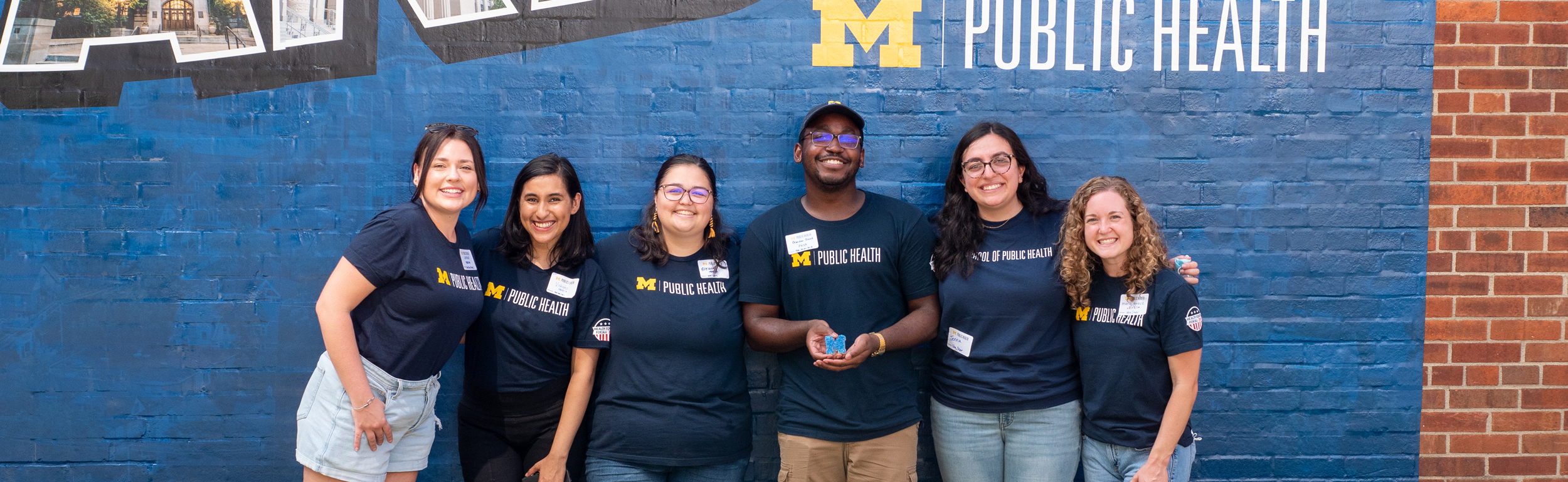 images of students jumping in front of a wall that says Michigan Public Health, Pursue A Healthier World For All, @umichsph