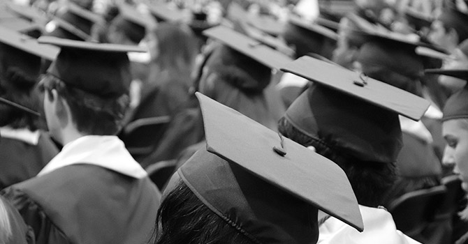 Black and white photo of students wearing a graduation cap and gown.