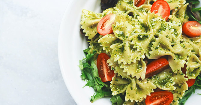 Bowl of bowtie pasta with pesto and tomatoes
