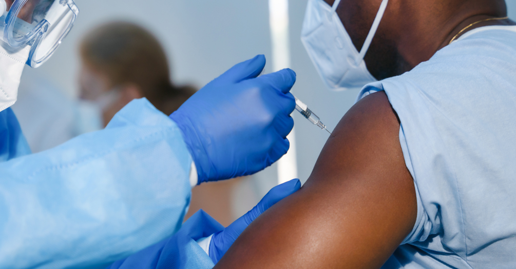 A person receives a vaccination in their left arm by a medical professional.