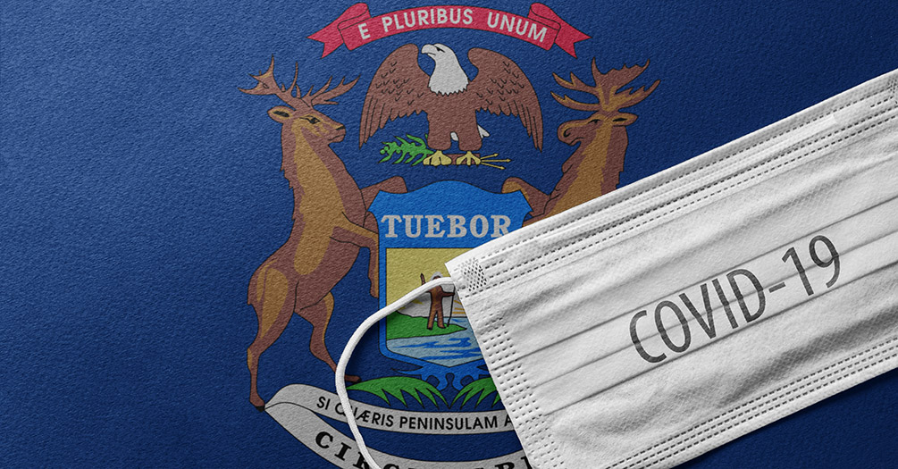 The state of Michigan flag and a surgical mask that says COVID-19.