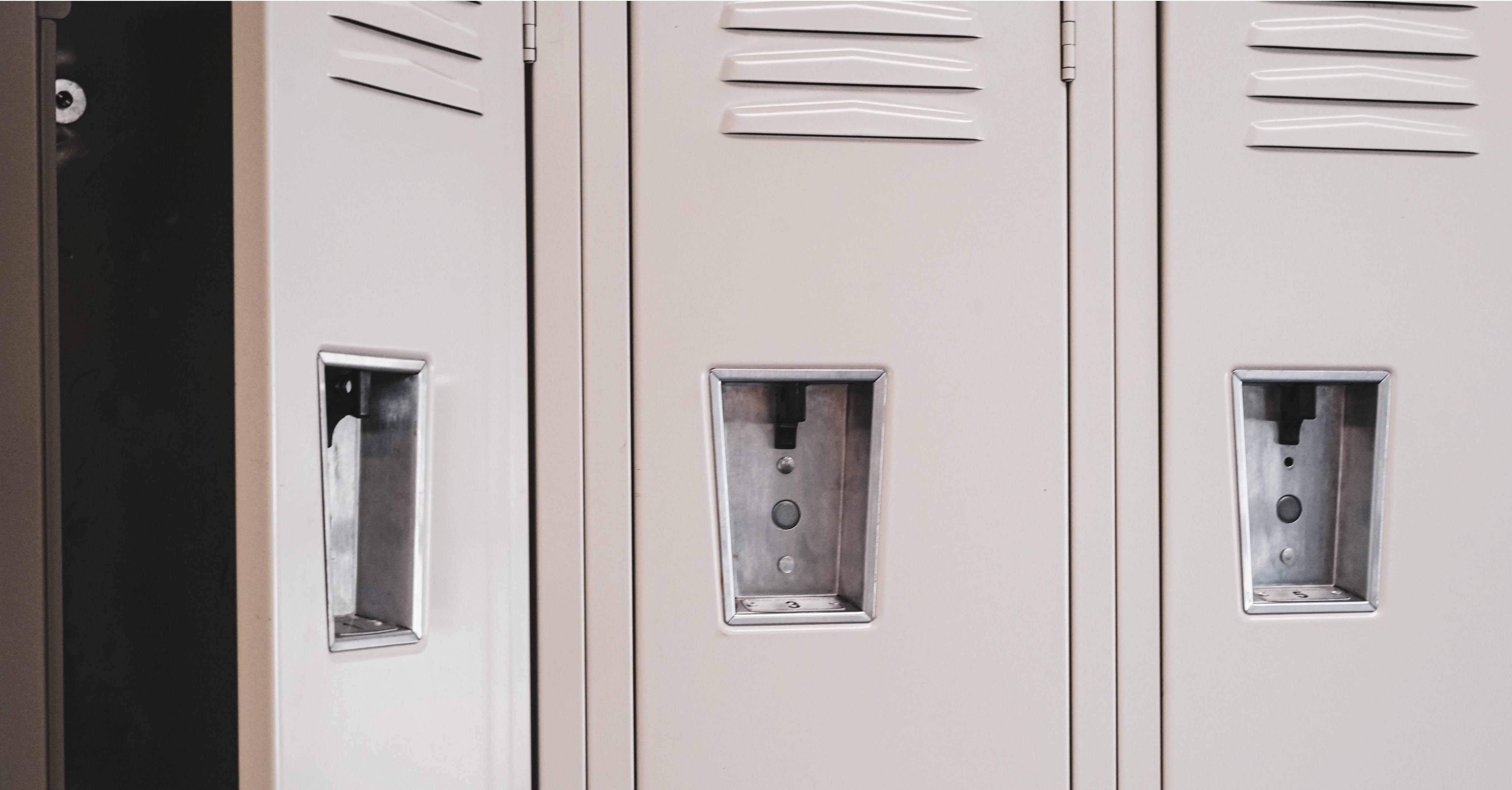 Three school lockers, with the first locker hanging open.